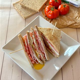 Club sandwich con Exquisa alle erbe, prosciutto, pomodori e uovo all’occhio di bue